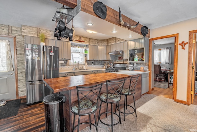 kitchen with stainless steel appliances, sink, tasteful backsplash, a breakfast bar area, and butcher block countertops