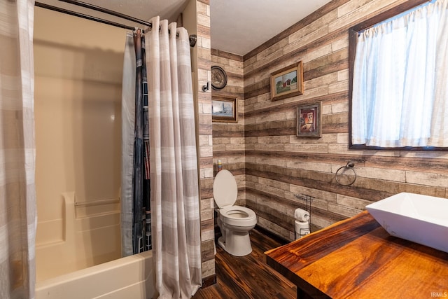 full bathroom featuring toilet, hardwood / wood-style flooring, wood walls, shower / tub combo with curtain, and sink