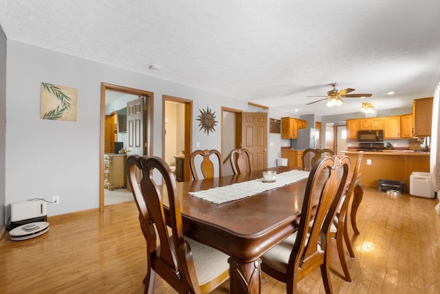 dining area with a textured ceiling, ceiling fan, and light hardwood / wood-style flooring