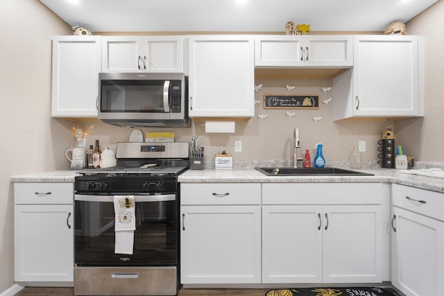 kitchen featuring appliances with stainless steel finishes, white cabinets, and sink