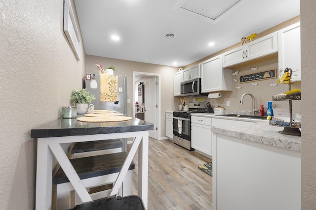 kitchen featuring white cabinets, appliances with stainless steel finishes, light hardwood / wood-style floors, and sink