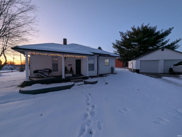 snow covered property featuring a garage and an outdoor structure