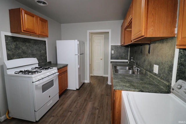 kitchen featuring white appliances, washer / clothes dryer, dark wood-type flooring, sink, and tasteful backsplash