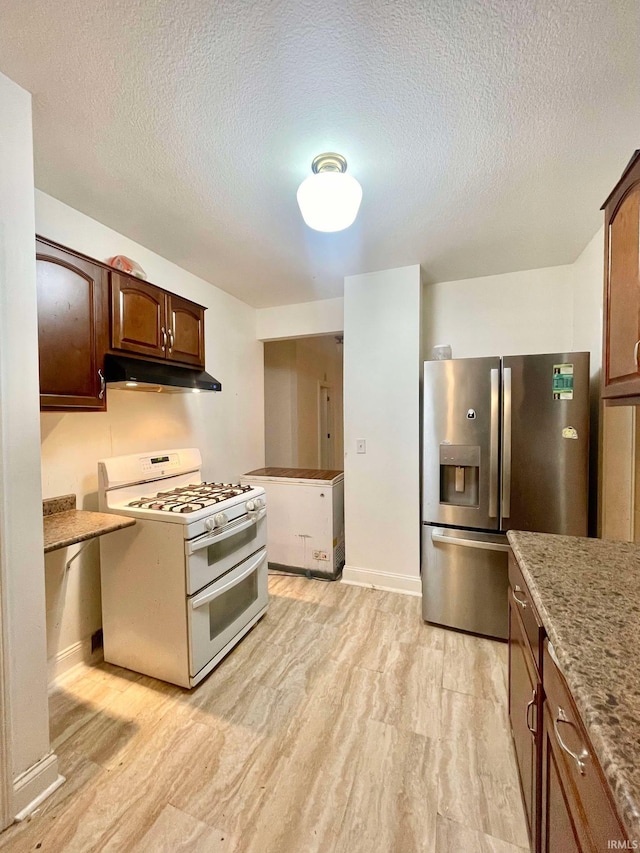 kitchen featuring a textured ceiling, double oven range, dark brown cabinets, and stainless steel fridge with ice dispenser