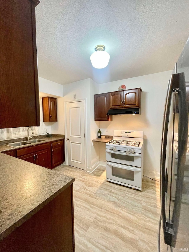 kitchen with sink, a textured ceiling, black fridge, light hardwood / wood-style flooring, and double oven range