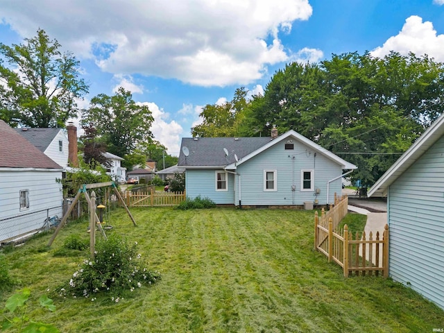 rear view of house with a lawn and a playground