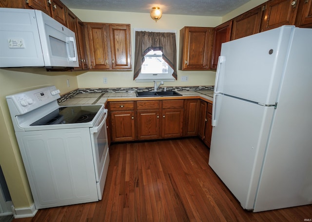 kitchen with white appliances, dark hardwood / wood-style flooring, and sink