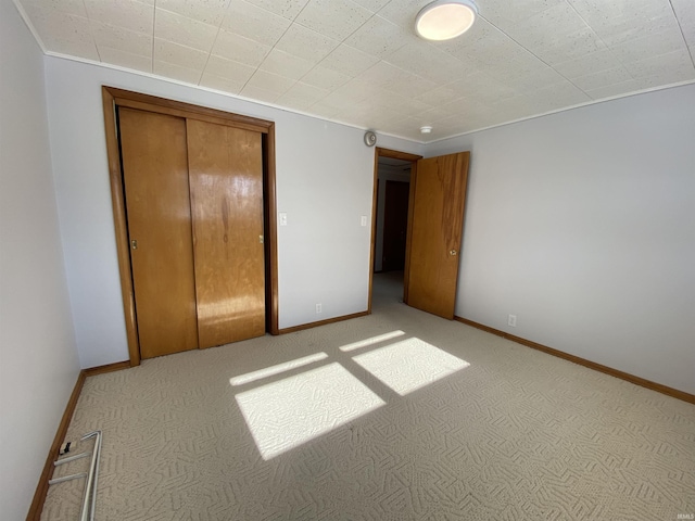 unfurnished bedroom with light colored carpet and a closet