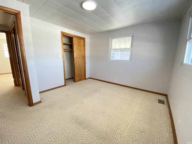 unfurnished bedroom featuring a closet and light colored carpet