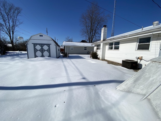 yard covered in snow featuring central AC unit and a shed