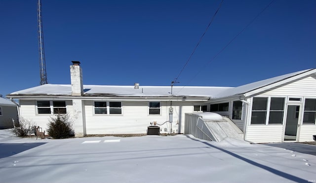 snow covered rear of property featuring central air condition unit