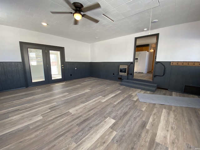 unfurnished living room featuring wood-type flooring, ceiling fan, and heating unit