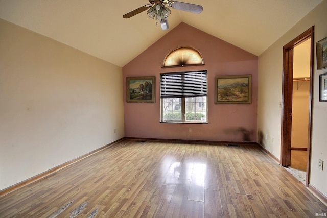 unfurnished bedroom with a closet, vaulted ceiling, light hardwood / wood-style floors, ceiling fan, and a spacious closet