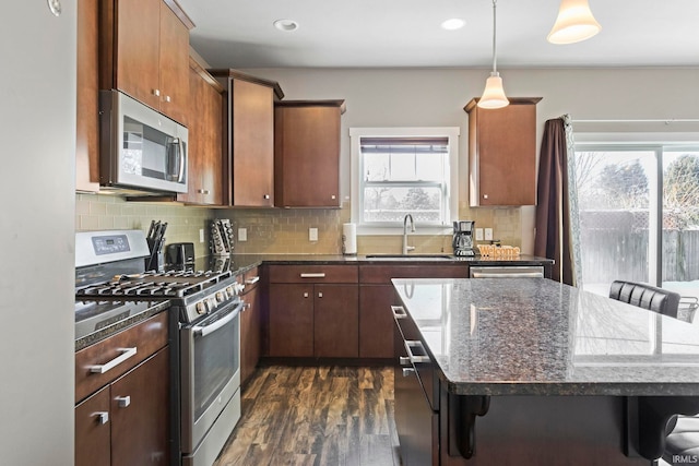 kitchen with stainless steel appliances, sink, a kitchen breakfast bar, tasteful backsplash, and dark hardwood / wood-style floors