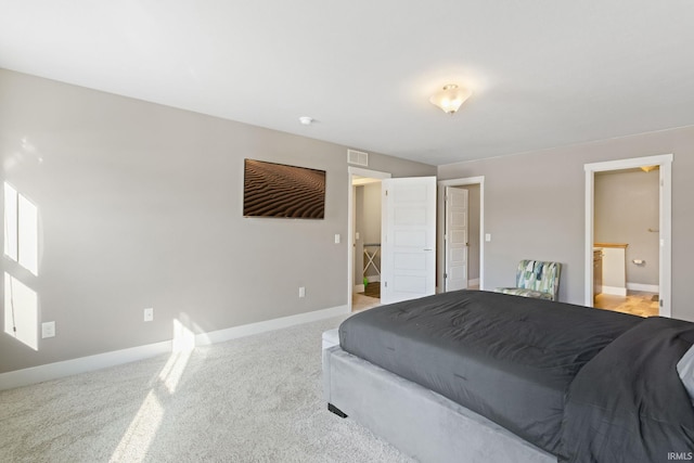 bedroom with ensuite bath and light colored carpet