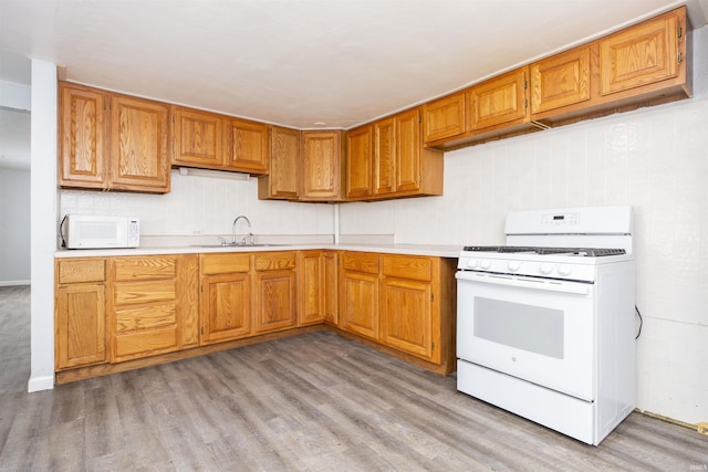 kitchen featuring white appliances, light hardwood / wood-style flooring, and sink