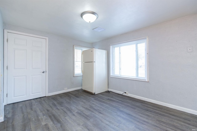 unfurnished bedroom with white refrigerator, dark hardwood / wood-style flooring, and a closet