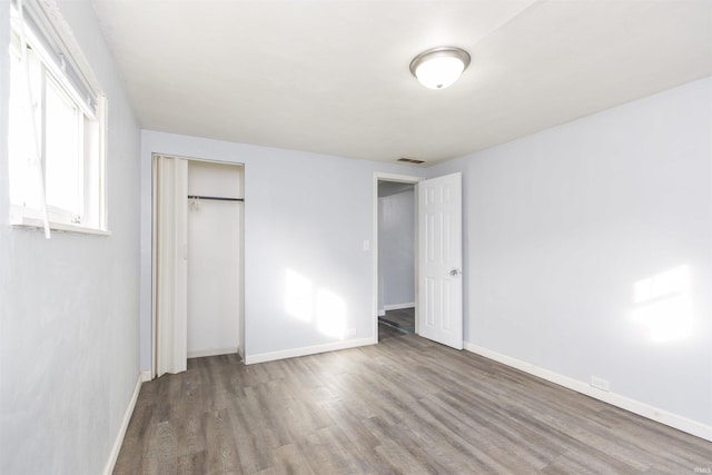 unfurnished bedroom with wood-type flooring and a closet