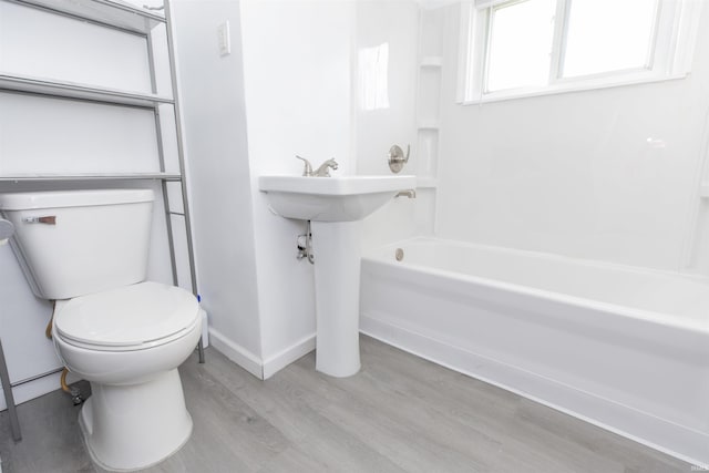 bathroom with wood-type flooring, tub / shower combination, and toilet