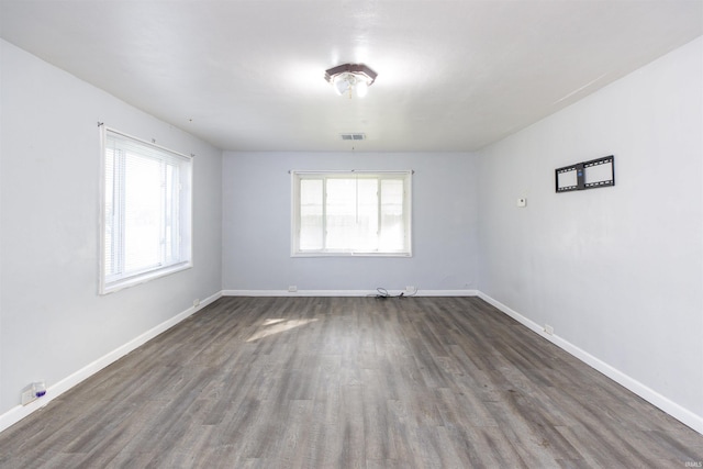 spare room with a healthy amount of sunlight and dark wood-type flooring