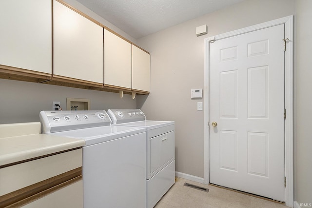 laundry room with washer and dryer, cabinets, and a textured ceiling