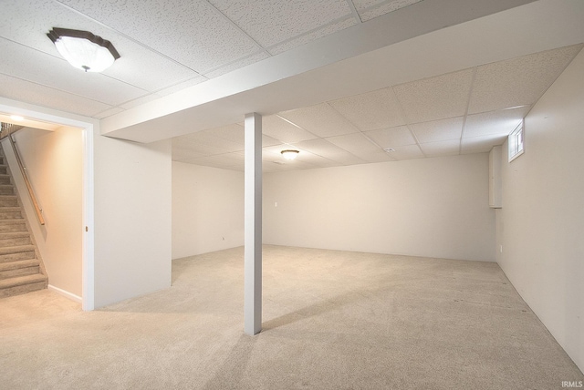 basement featuring light colored carpet and a paneled ceiling