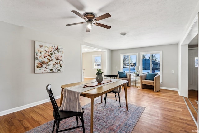 dining room with a textured ceiling, ceiling fan, and light hardwood / wood-style flooring