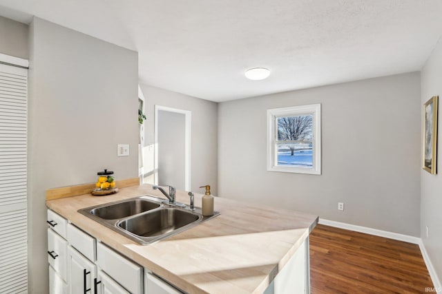 kitchen featuring sink, white cabinetry, and dark wood-type flooring