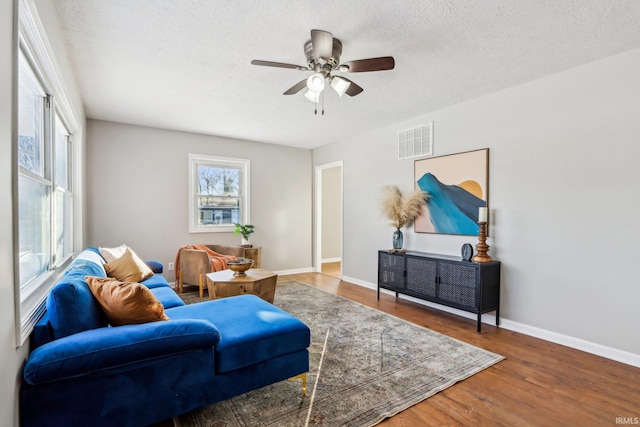 living room with a textured ceiling, ceiling fan, and wood-type flooring