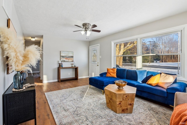 living room with a textured ceiling, ceiling fan, and dark hardwood / wood-style floors