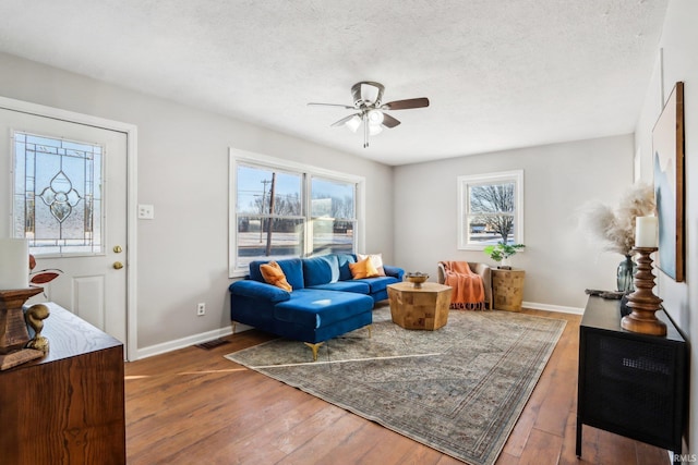 living room featuring a textured ceiling, ceiling fan, and dark wood-type flooring