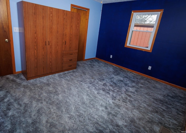 unfurnished bedroom featuring dark carpet, a closet, and a textured ceiling