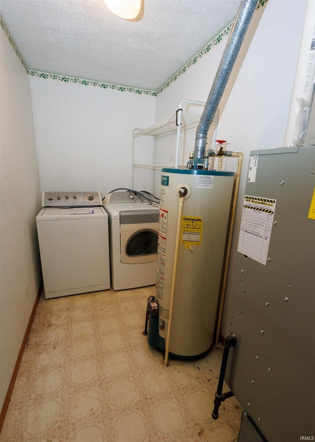 clothes washing area with water heater, a textured ceiling, and washing machine and dryer