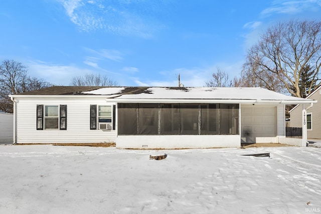 snow covered property featuring a garage and a sunroom