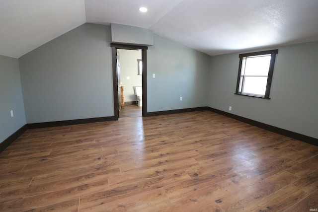 additional living space with vaulted ceiling and dark wood-type flooring