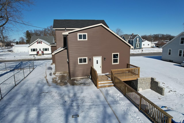 snow covered back of property with a deck