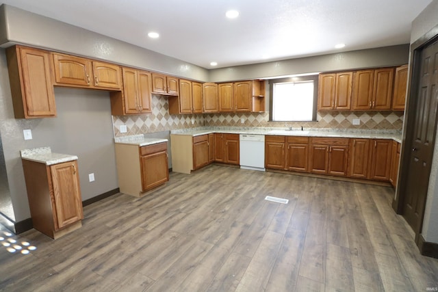 kitchen featuring dishwasher, wood-type flooring, sink, and decorative backsplash