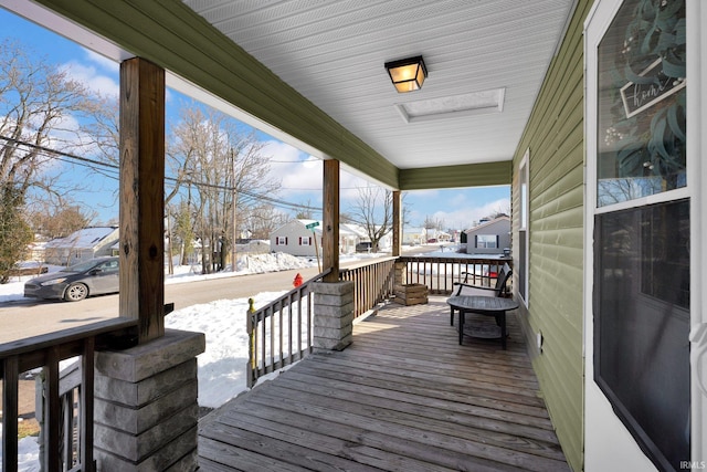 snow covered deck featuring a porch