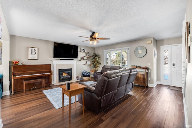 living room with a fireplace, a textured ceiling, ceiling fan, and dark hardwood / wood-style flooring