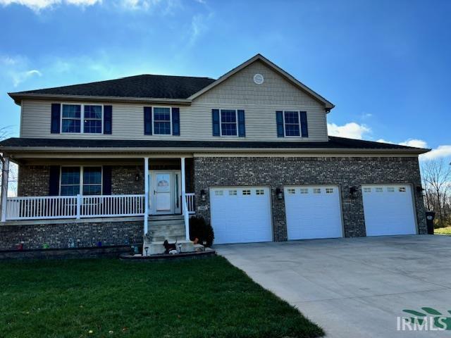 view of property with a garage, a front lawn, and covered porch