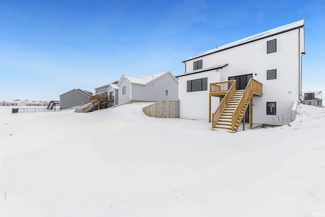 snow covered back of property with a wooden deck