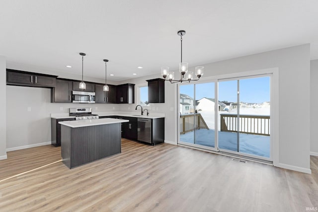 kitchen with sink, stainless steel appliances, a kitchen island, and hanging light fixtures