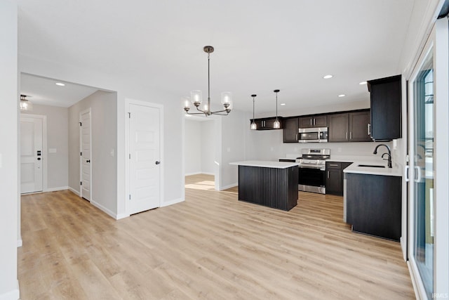 kitchen with appliances with stainless steel finishes, pendant lighting, a kitchen island, sink, and an inviting chandelier