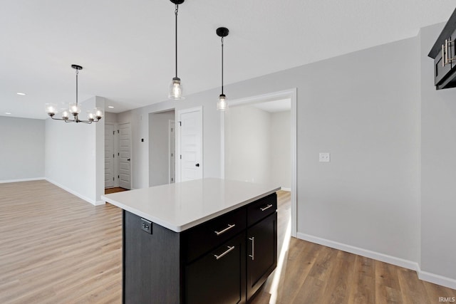 kitchen featuring a notable chandelier, light hardwood / wood-style floors, decorative light fixtures, and a kitchen island