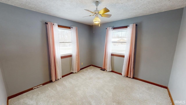 carpeted spare room with a textured ceiling and ceiling fan