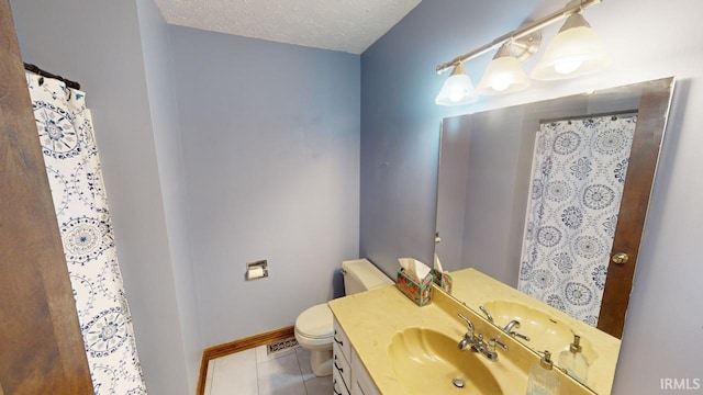 bathroom with a textured ceiling, vanity, tile patterned floors, and toilet