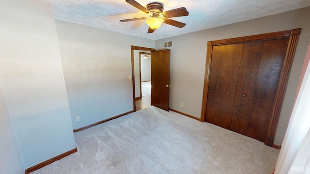 unfurnished bedroom featuring a closet, a textured ceiling, ceiling fan, and light carpet