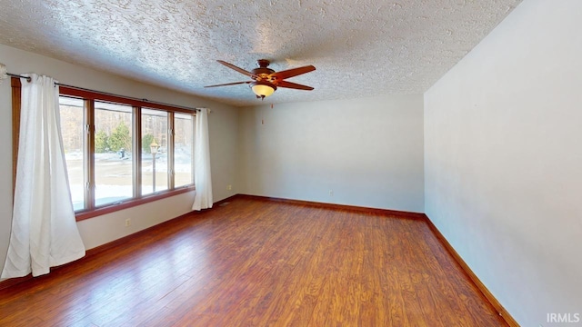 empty room with a textured ceiling, ceiling fan, and dark hardwood / wood-style flooring