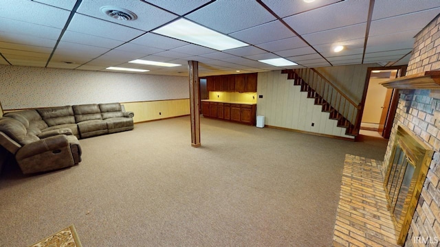 unfurnished living room with wooden walls, a brick fireplace, and light carpet