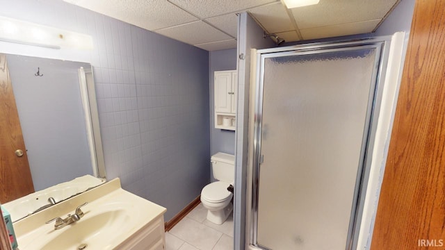 bathroom with tile patterned flooring, toilet, a paneled ceiling, vanity, and a shower with door